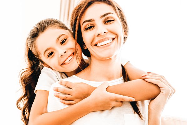 young girl hugging mother and smiling