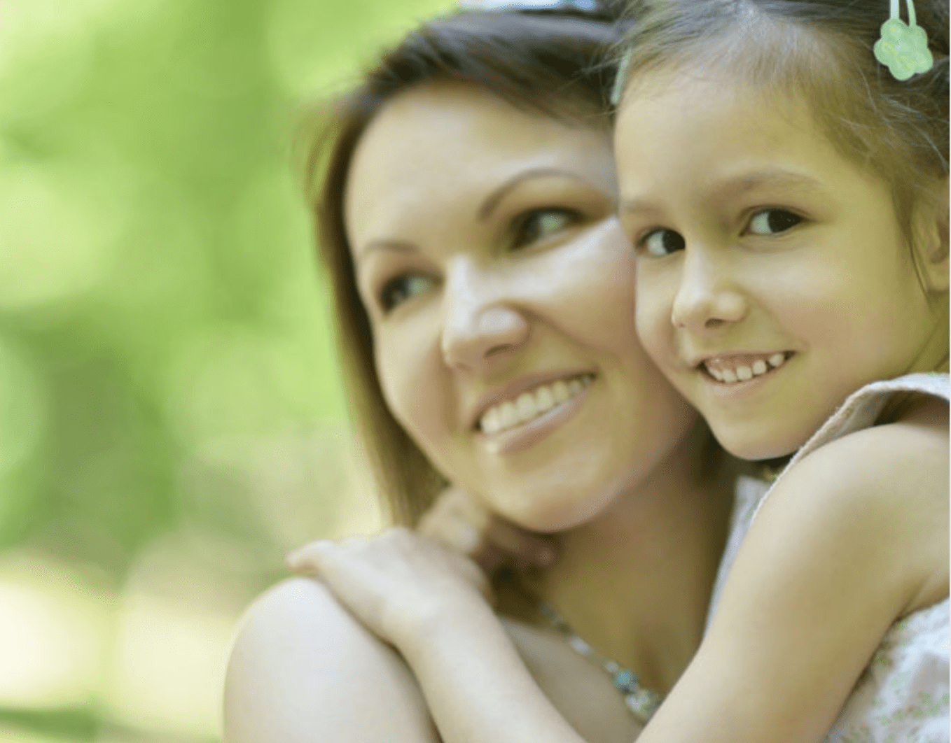 Mother and daughter hugging with green blurry background