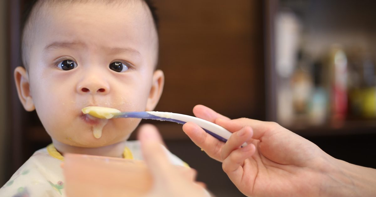infant being fed baby food by woman with spoon