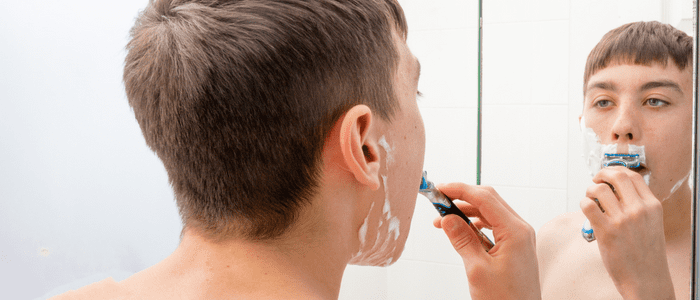 Teenage boy shaving during a stage of puberty