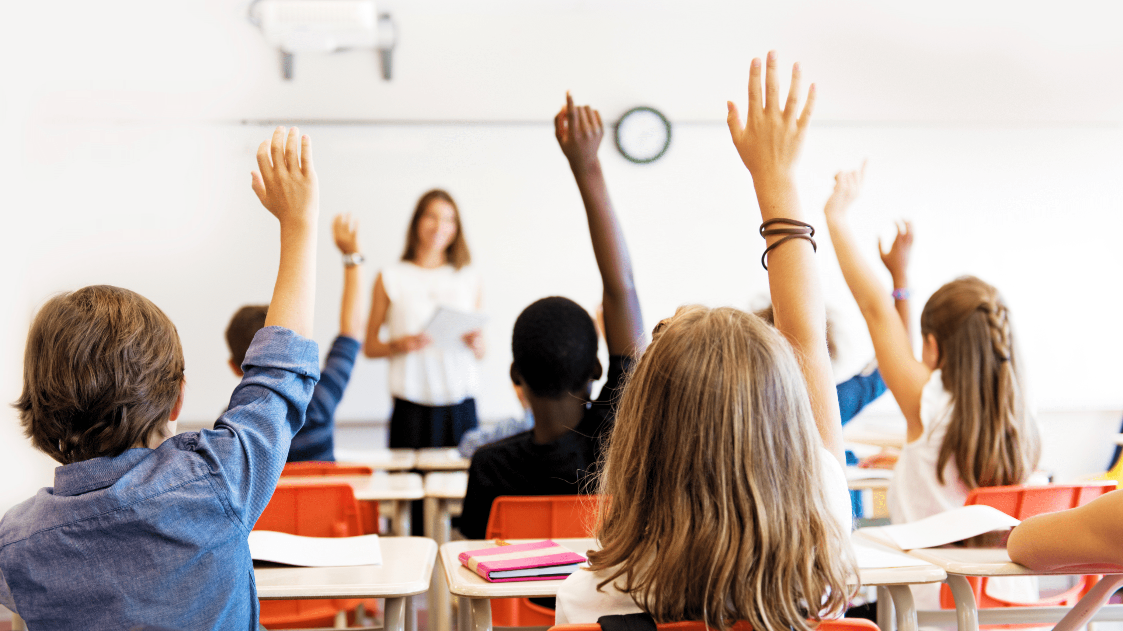 Kids raising their hands in a classroom
