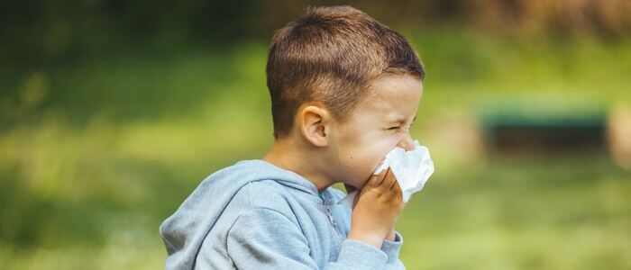 202308_tyc_blogs Young child blowing nose outdoors during spring allergy season in Northern Colorado